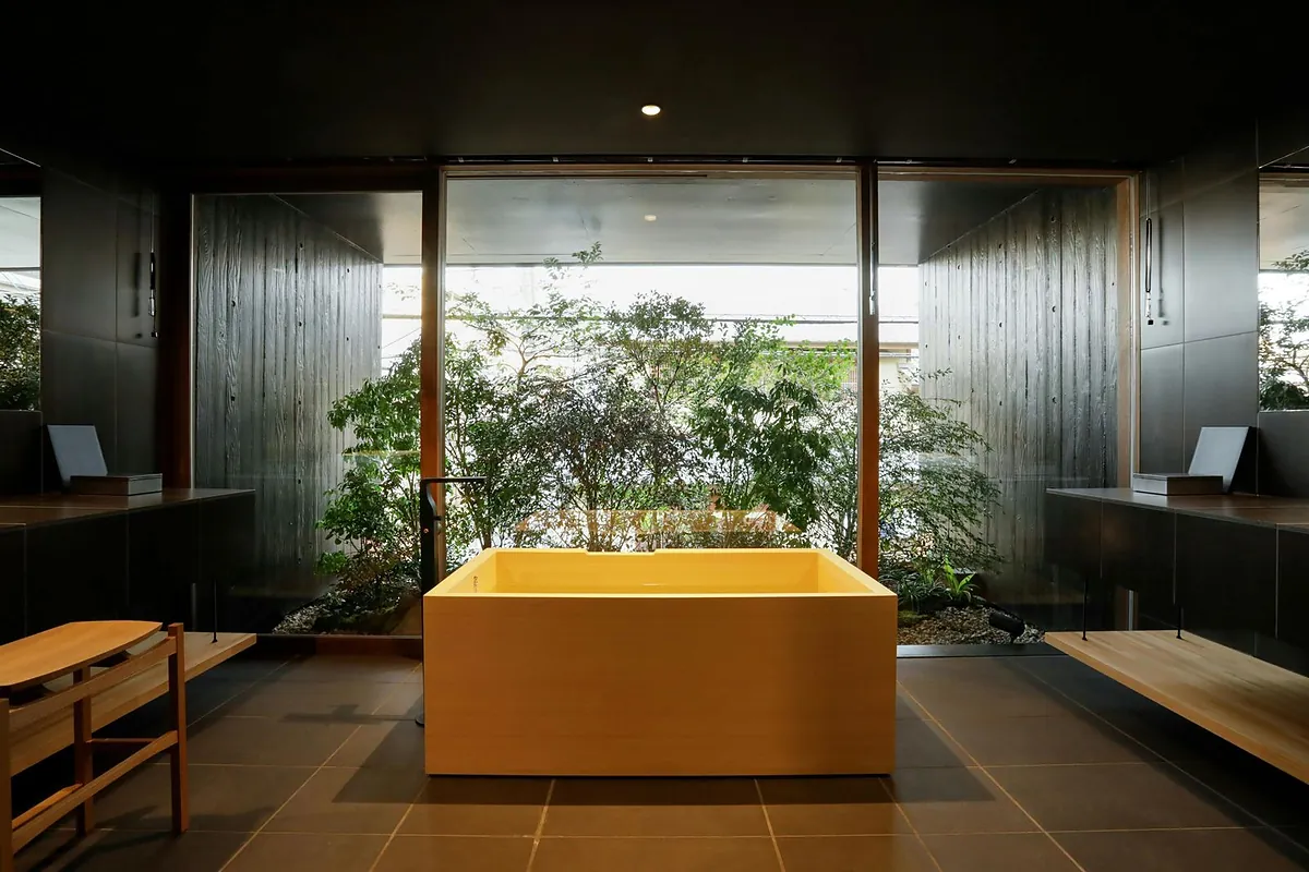 SOWAKA, a yellow hinoki soaking tub in a dark bathroom open to bamboo, Kyoto