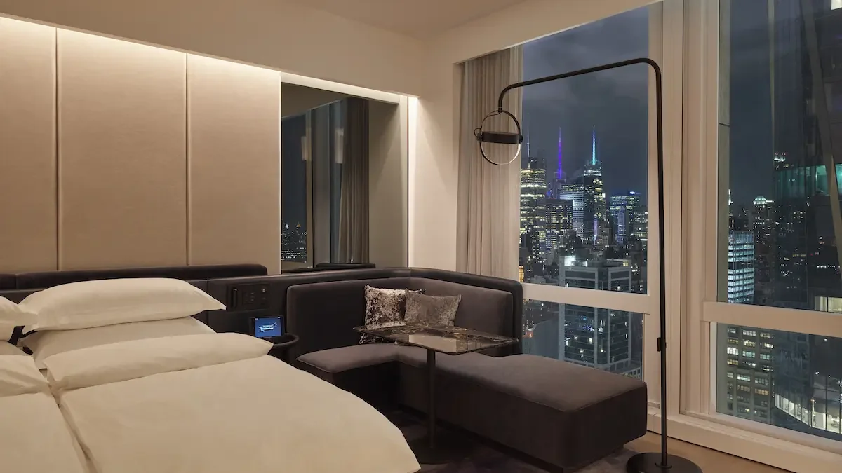 Equinox Hotel New York — a guest room with the skyline behind the bed