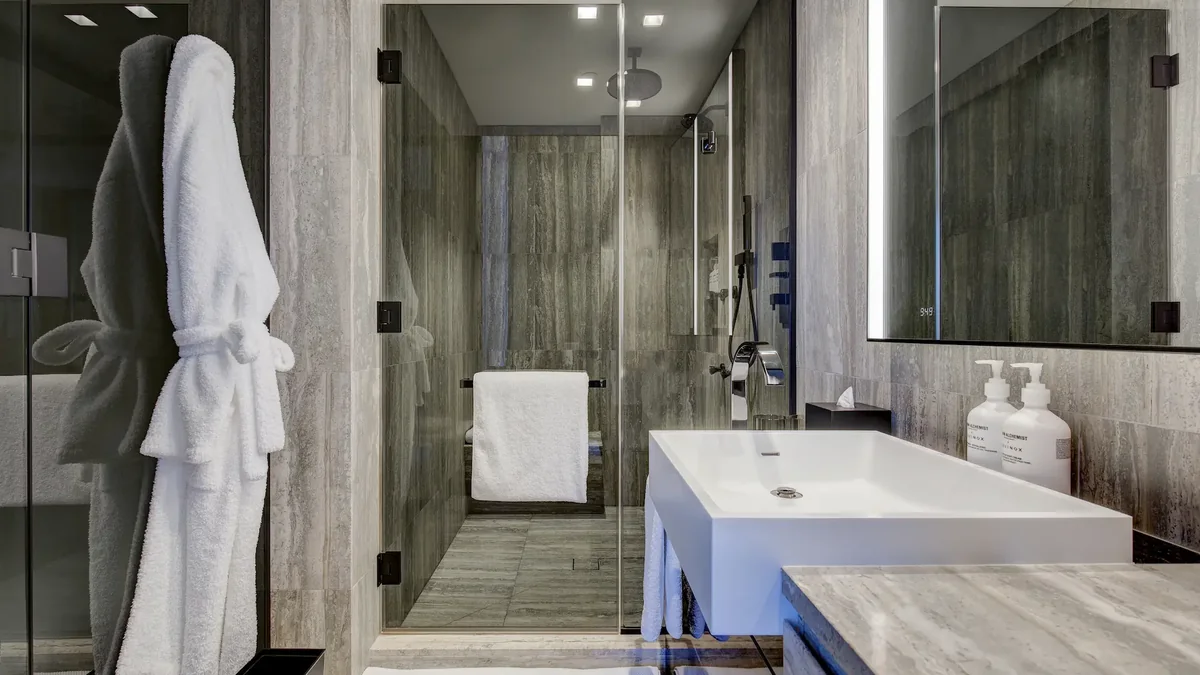 Equinox Hotel New York — a bathroom in dark stone and glass