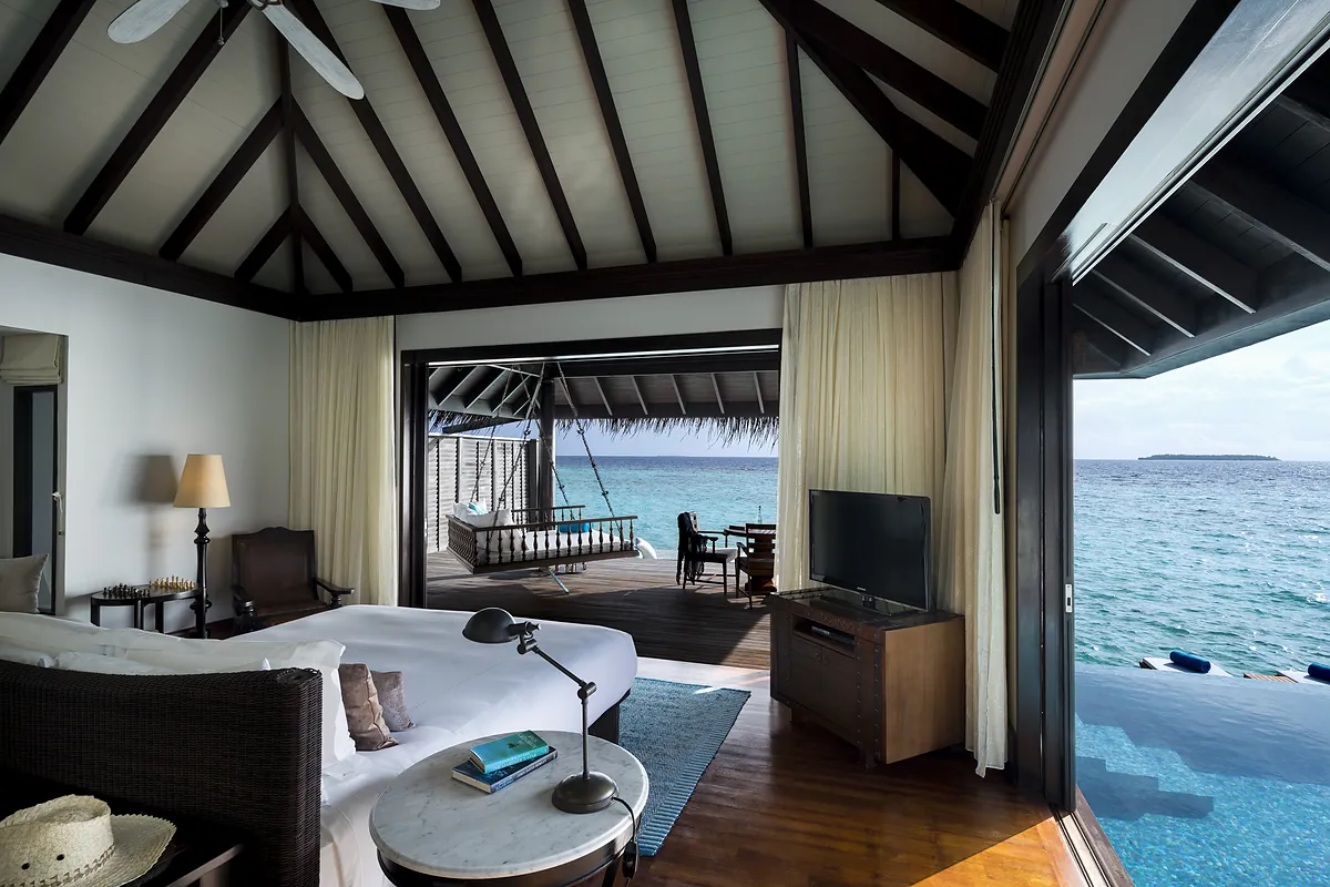 Overwater pool villa bedroom opening onto the deck at Anantara Kihavah Maldives Villas