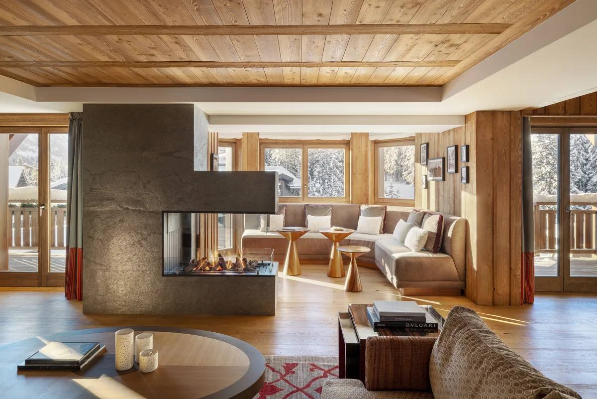 Suite living room with central stone fireplace at Hotel Barriere Les Neiges