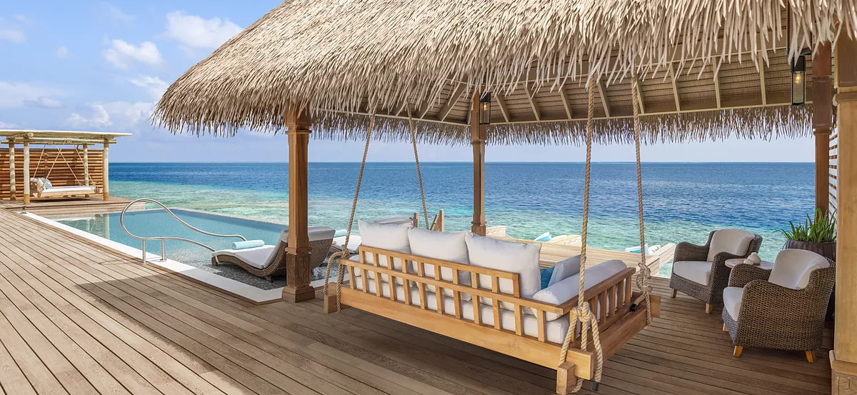 Thatched overwater villa pavilion and daybed swing at Waldorf Astoria Maldives Ithaafushi