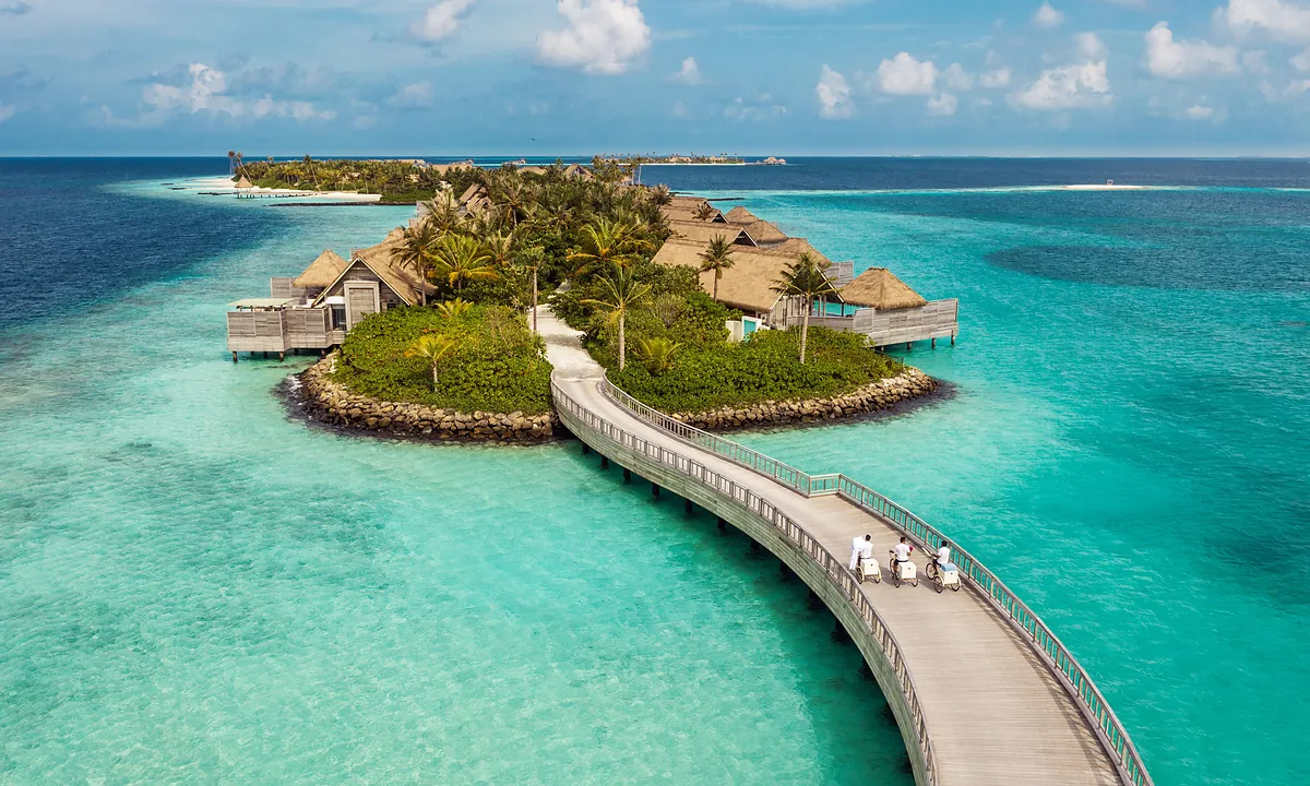 Aerial view of the island and overwater villa jetty at Waldorf Astoria Maldives Ithaafushi