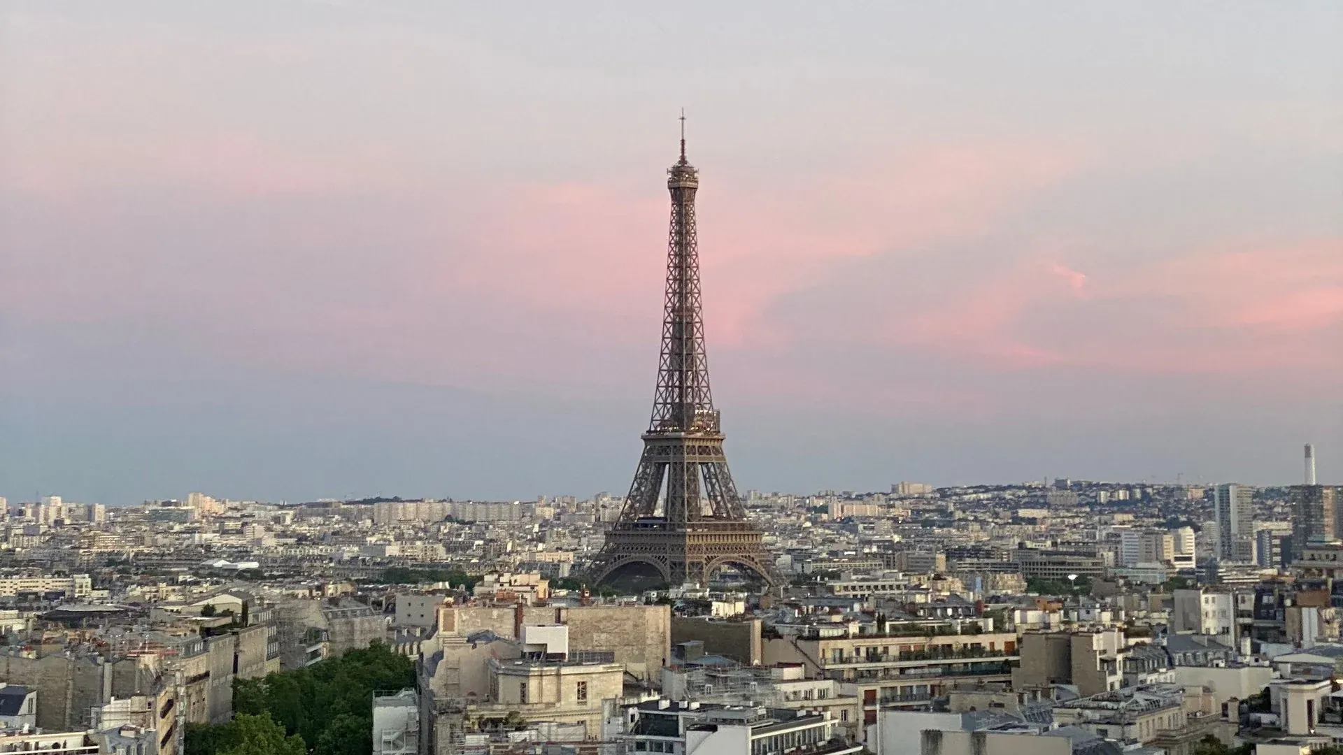 The Eiffel Tower rising above the Haussmann rooftops of Paris at sunset
