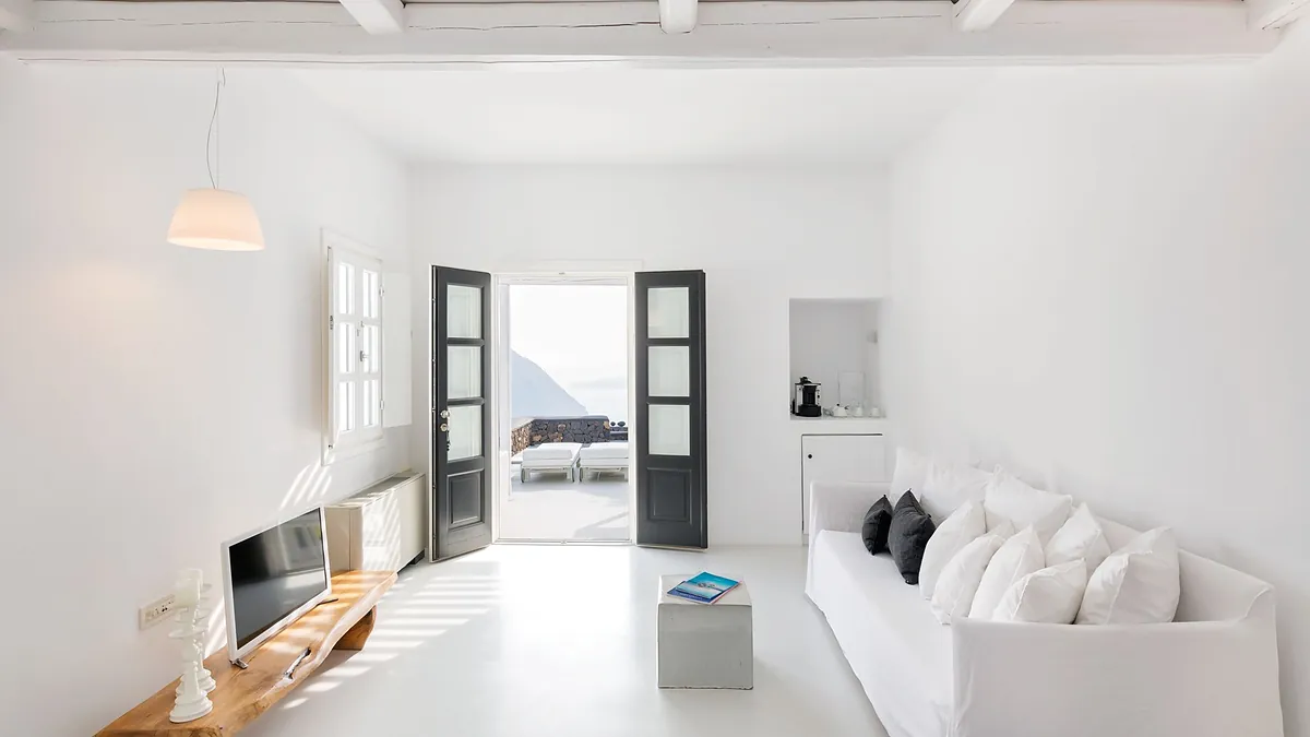 Bright white living area sofa tv at Aenaon Villas in Santorini