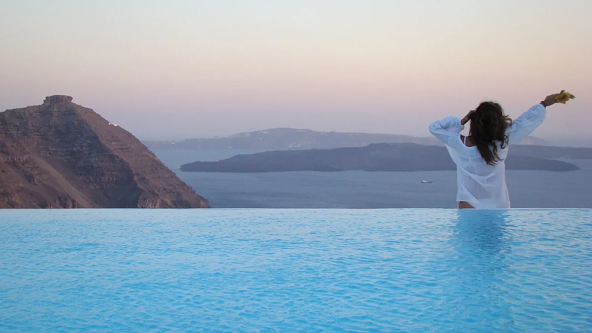 Pool terrace at Aenaon Villas in Firostefani with a panoramic view across the Santorini caldera