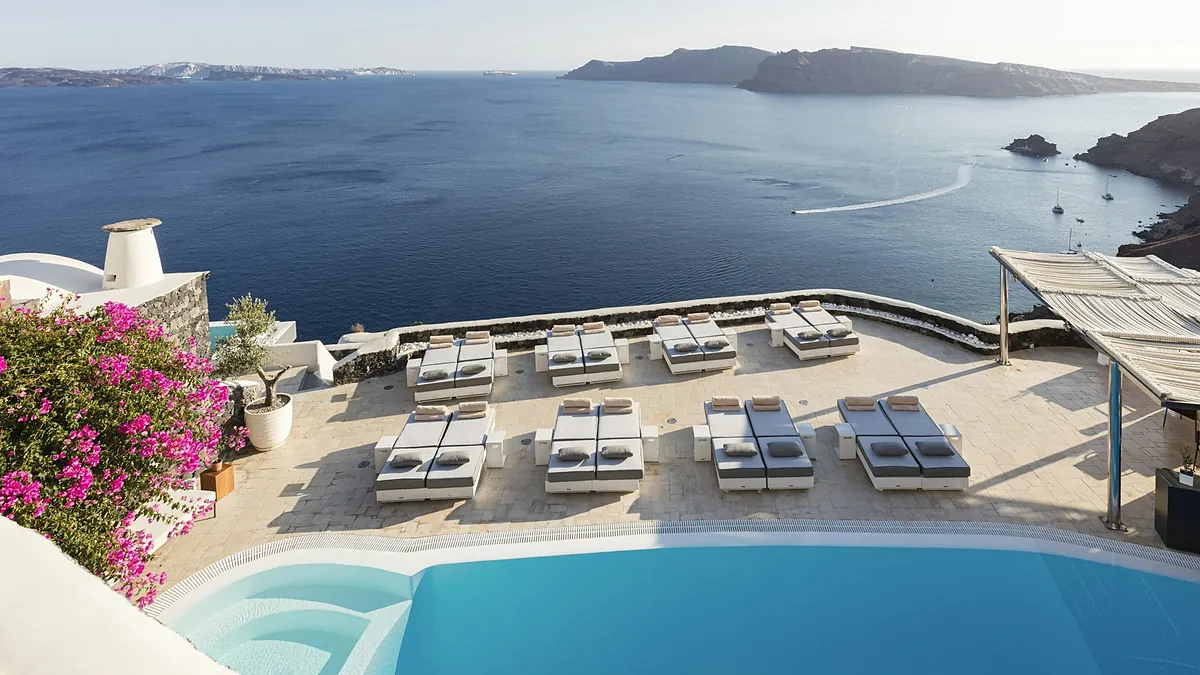 The main infinity pool at Canaves Oia Suites carved into the Oia cliff with volcanic caldera views beyond