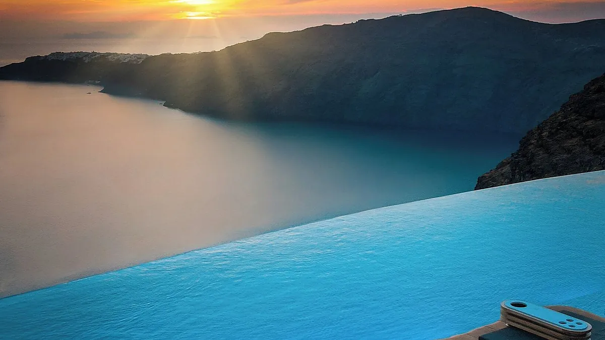The main infinity pool at Cavo Tagoo Santorini in Imerovigli glowing at sunset above the caldera