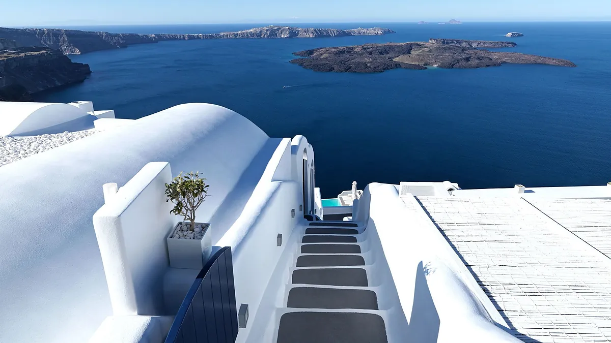 Whitewashed cliffside exterior of Katikies Chromata hotel in Imerovigli, Santorini, above the caldera