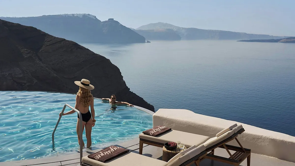 Cliffside infinity pool and terraced white suites at Mystique, a Luxury Collection Hotel in Oia, Santorini