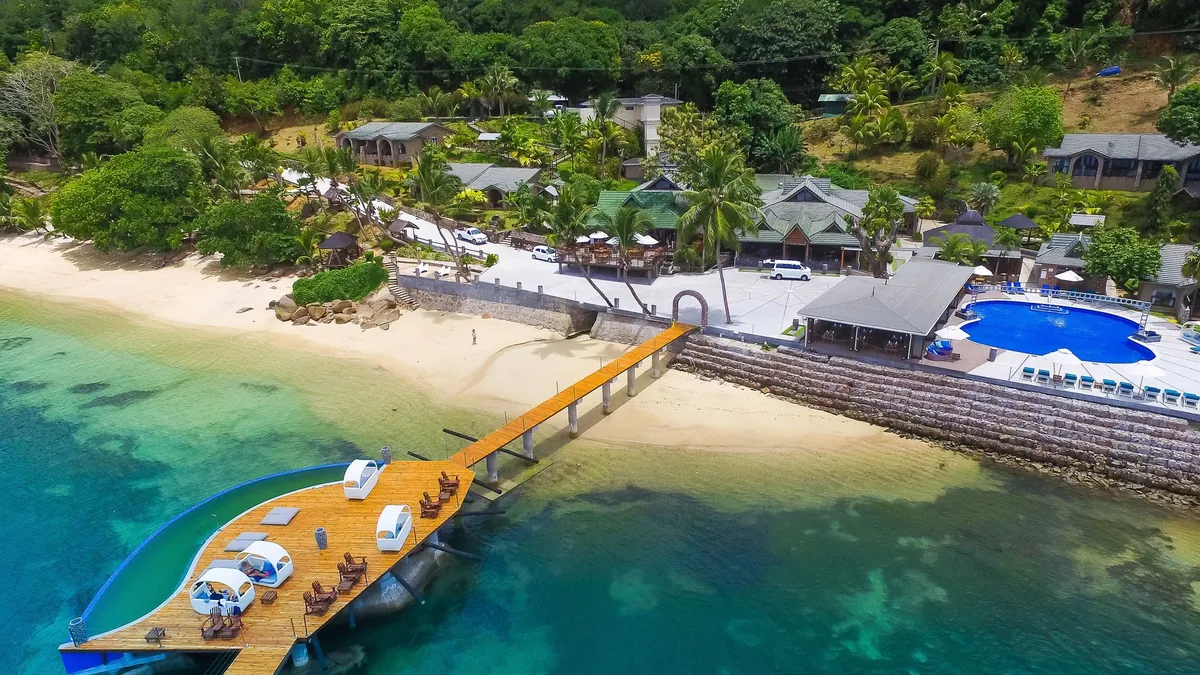 Aerial view of the beachfront jetty and pool deck at Coco de Mer and Black Parrot Suites, Praslin, Seychelles