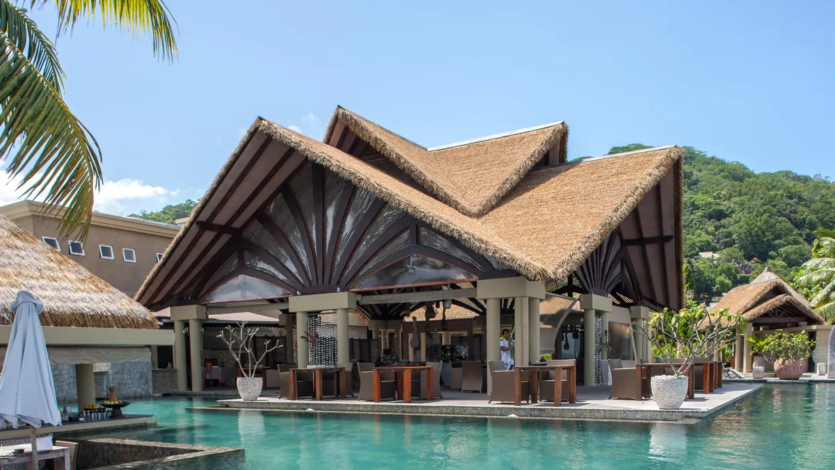Thatched roof restaurant and main pool complex at Le Domaine de L'Orangeraie, La Digue, Seychelles