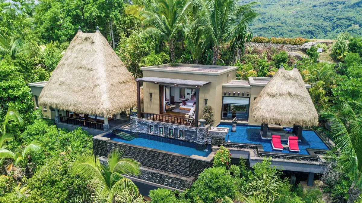Aerial view of a hillside villa with twin thatched pavilions and a private pool at Anantara Maia Seychelles Villas, Anse Louis, Mahé