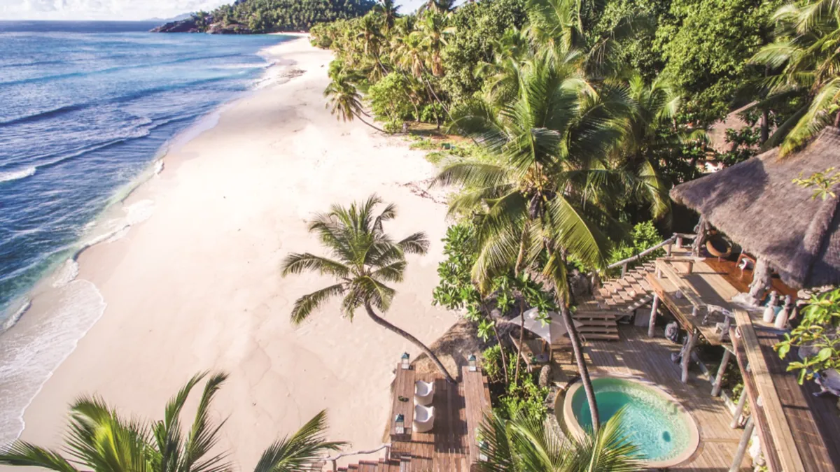 Aerial view of a beachfront villa with private plunge pool and thatched roof at North Island, Seychelles