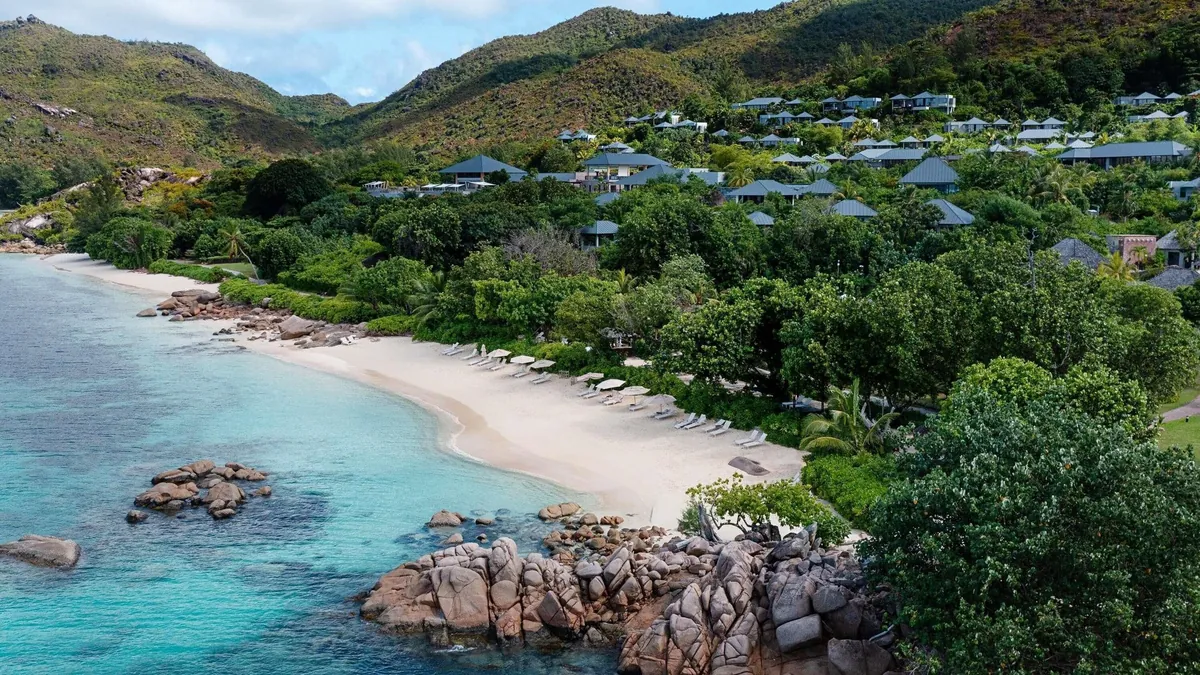 Hillside villas above Anse Takamaka beach with granite outcrops at Raffles Seychelles, Praslin