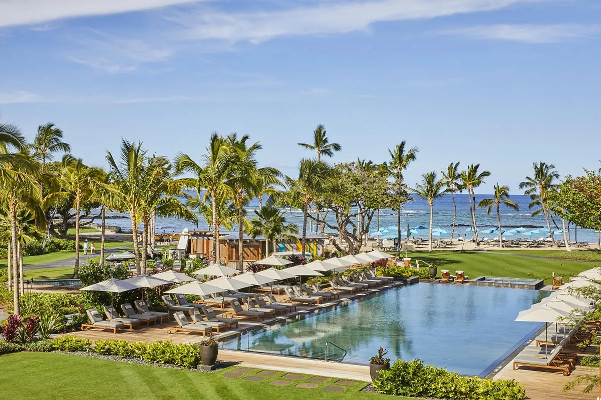 Contemporary resort infinity pool at dusk overlooking lava fields and the ocean on the Kohala Coast