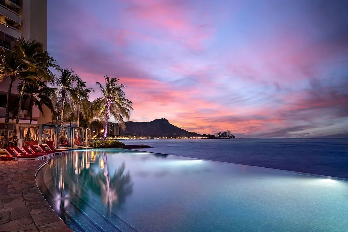 Oceanfront hotel in Honolulu Oahu with a palm lined pool, beach and Diamond Head in the distance